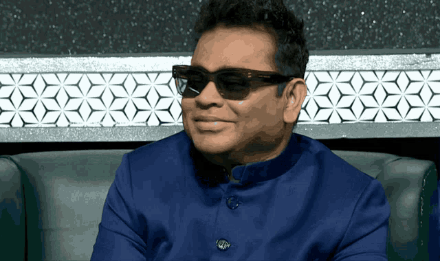 a man wearing sunglasses and a blue shirt is sitting on a green couch