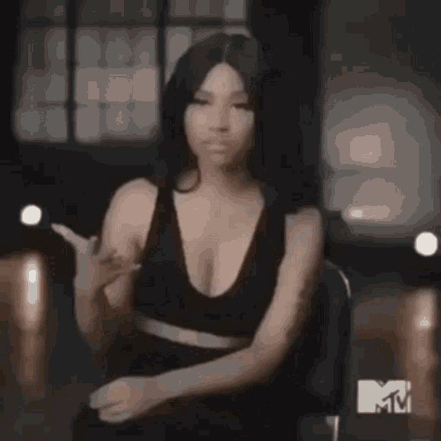 a woman in a black dress is standing in a dark room and looking at the camera .