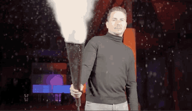 a man in a black turtleneck holds a torch in his hand