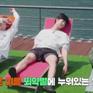 a man is laying on a lounge chair next to another man on a dock .