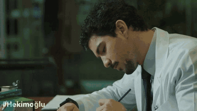 a man in a lab coat is writing on a piece of paper with the hashtag #hekimoglu