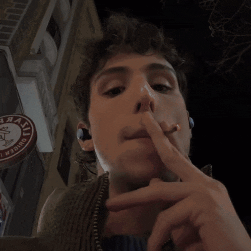 a man smoking a cigarette in front of a sign that says " chicken "
