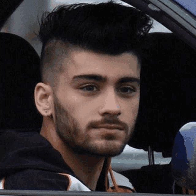 a young man with a beard is sitting in a car .