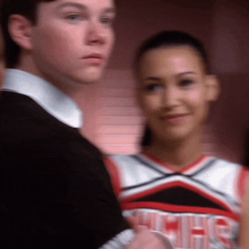 a cheerleader wearing a uniform that says high school musical is standing next to a boy