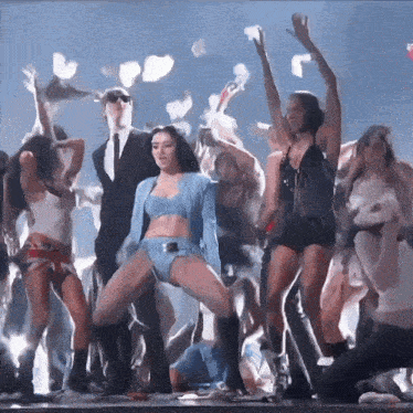 a group of people are dancing on a stage and one of them is wearing a blue top