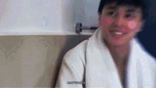 a man in a white robe and hat is smiling .