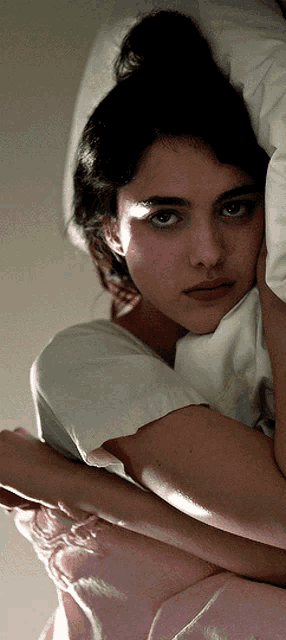 a woman in a white shirt is holding a white pillow