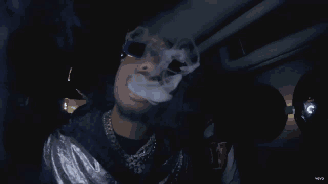 a man wearing sunglasses is smoking a cigarette while wearing a shirt with the letter n on it