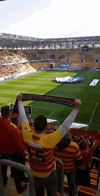 a man in a yellow shirt with the number 5 on it stands in a stadium