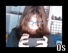 a girl wearing glasses is playing a video game on her cell phone
