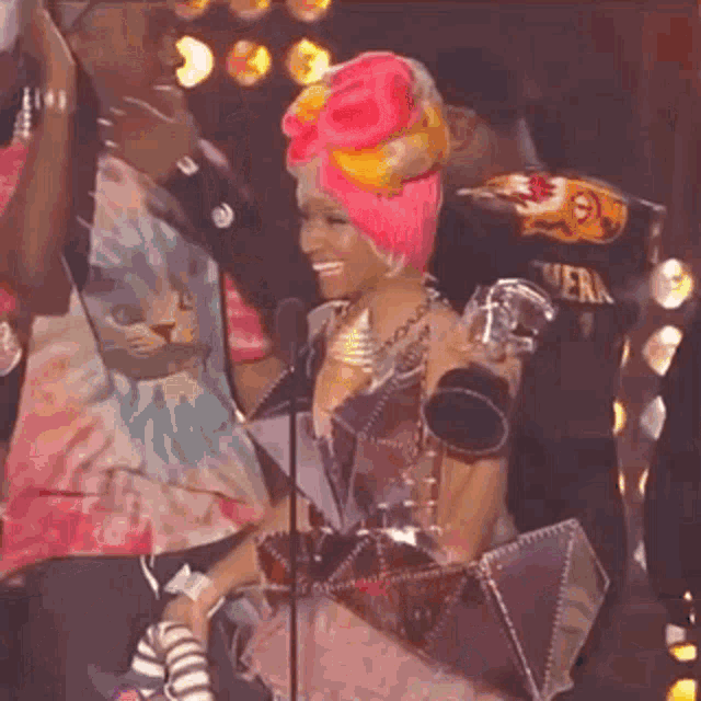 a woman with pink hair is holding a trophy in front of a microphone ..