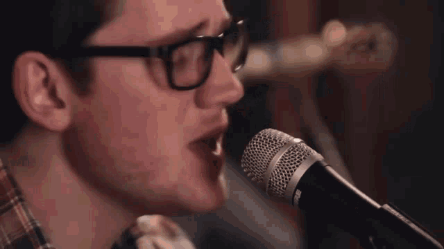 a man singing into a shure microphone with glasses on