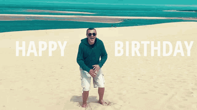 a man is standing on a sandy beach with the words happy birthday behind him