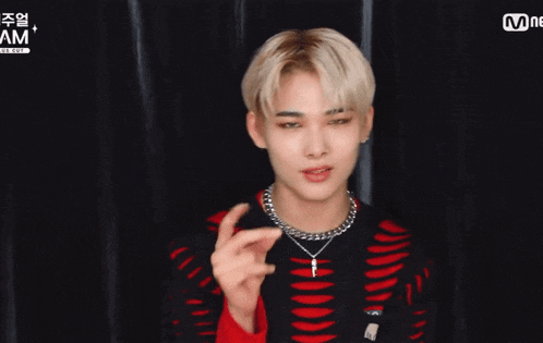a young man wearing a black and red sweater is making a heart sign