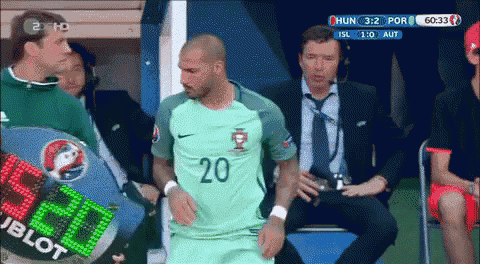 a soccer player with the number 20 on his jersey stands in front of a scoreboard