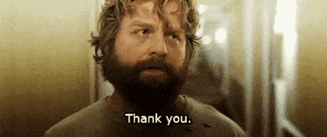 a man with a beard is standing in a room and saying thank you .