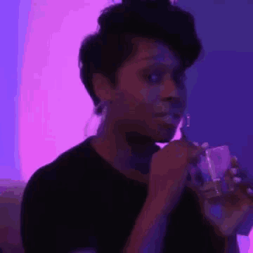 a woman is drinking from a glass in a dark room .