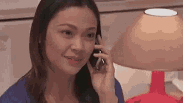 a woman in a purple shirt is talking on a cell phone .