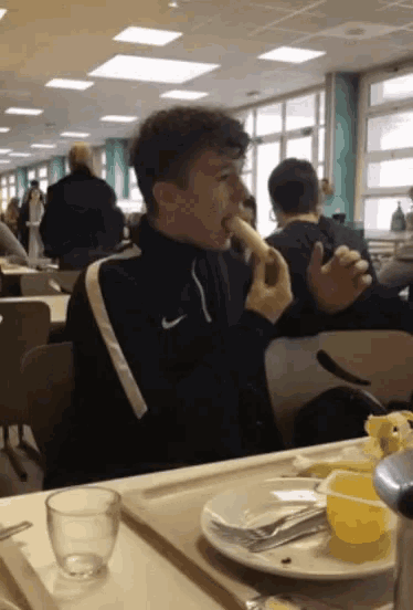 a man wearing a nike jacket is eating something