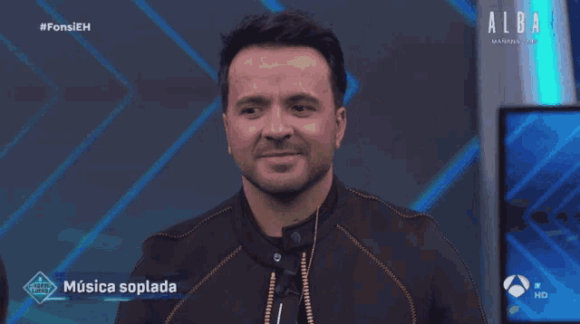 a man stands in front of a screen that says alba