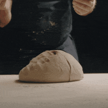 a person kneading a ball of dough on a counter