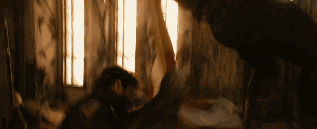 a man and a woman are fighting in a room with a window .