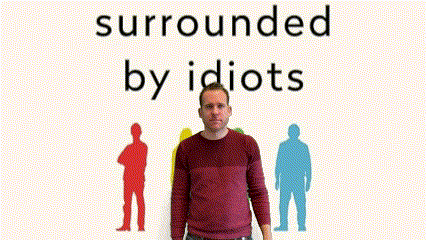 a man in a red sweater is standing in front of a sign that says surrounded by idiots