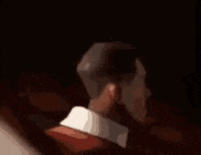 a close up of a man 's face in a dark room with a blurred background .
