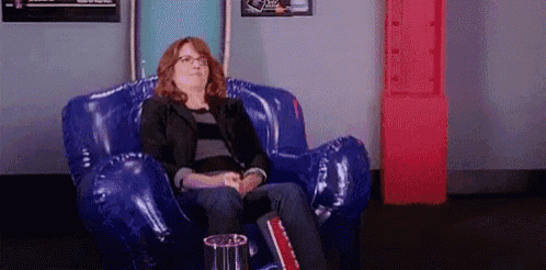 a woman is sitting in a blue inflatable chair with popcorn in front of her .