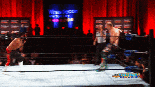 a wrestling ring with a sign that says wrestlecon in the background