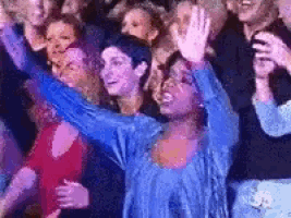 a group of people are standing in a crowd with their arms outstretched