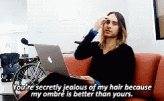 a man is sitting on a couch with a laptop and saying " you 're secretly jealous of my hair