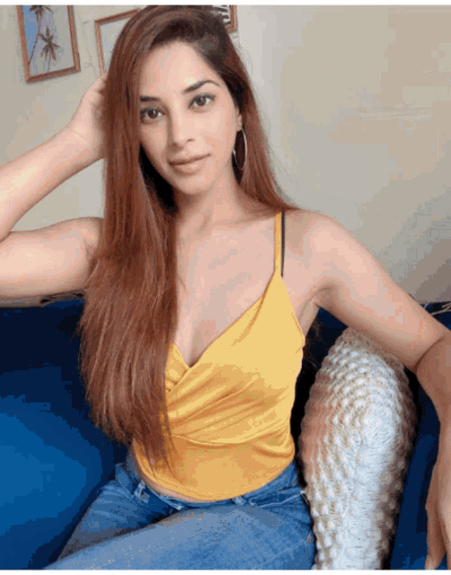 a woman is sitting on a blue couch wearing a yellow top