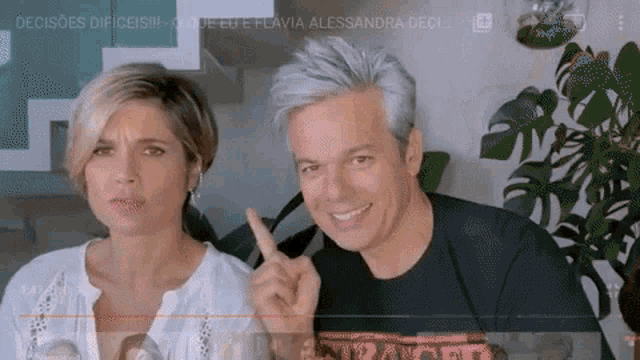 a man and a woman are sitting next to each other and the man is pointing