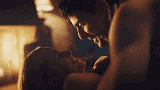 a man and a woman are kissing and looking at each other