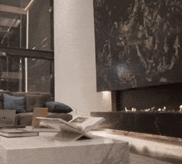 a living room with a fireplace and a book on a coffee table