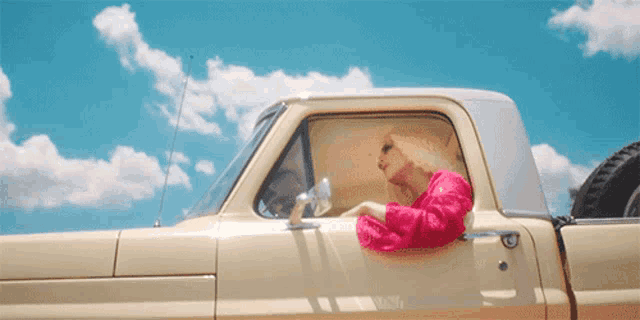 a woman in a pink dress is driving a truck