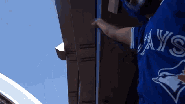 a man wearing a blue jays jersey is working on a roof