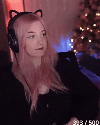 a woman with pink hair is wearing headphones with cat ears on her head
