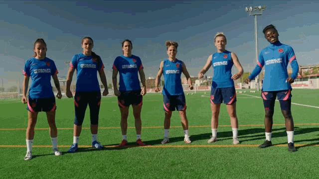 a group of female soccer players are standing on a field wearing shirts that say herbalife