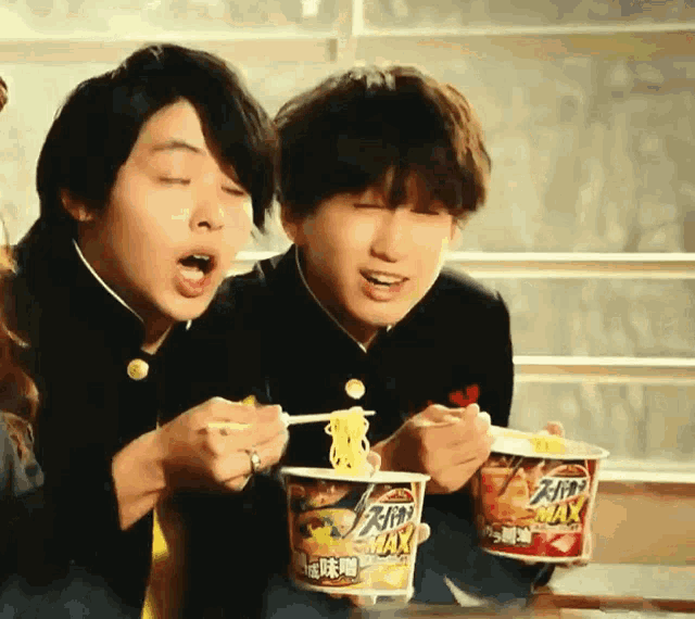 two young boys are eating noodles from cups that say max