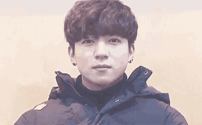 a close up of a young man wearing a black jacket and a black turtleneck .