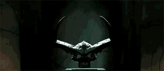 a man in a green jacket is holding a gun in his hand in a dark room .