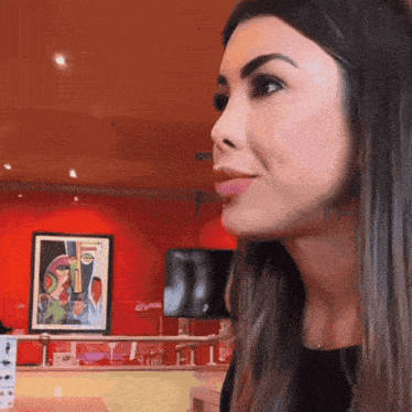 a woman sitting in front of a red wall with a picture on it that says ' coca cola ' on it