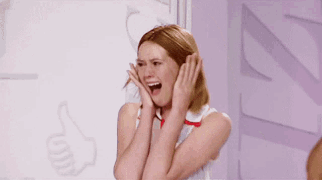 a woman is covering her ears with her hands while screaming .