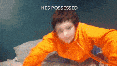 a person in an orange hoodie is laying on a bed with the words " hes possessed " on the bottom