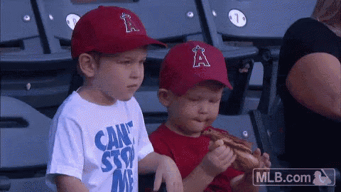 two young boys wearing angels hats are eating a hot dog