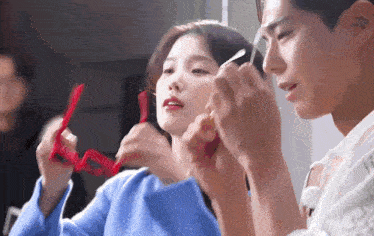 a man and a woman are looking at each other while holding a red object .