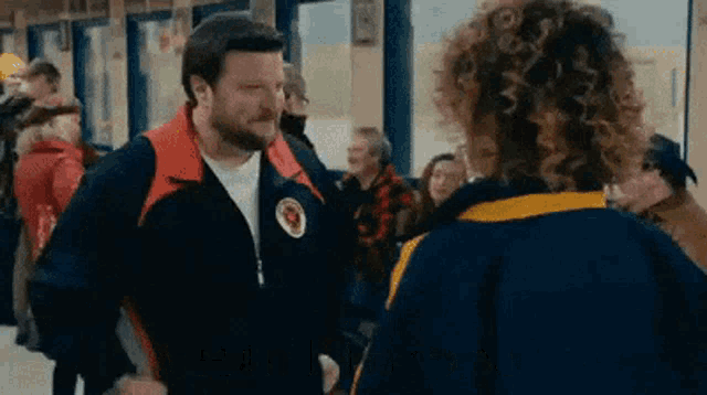 a man with a beard is talking to a woman in a crowded room .