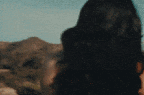 a blurry picture of a woman standing in front of a mountain